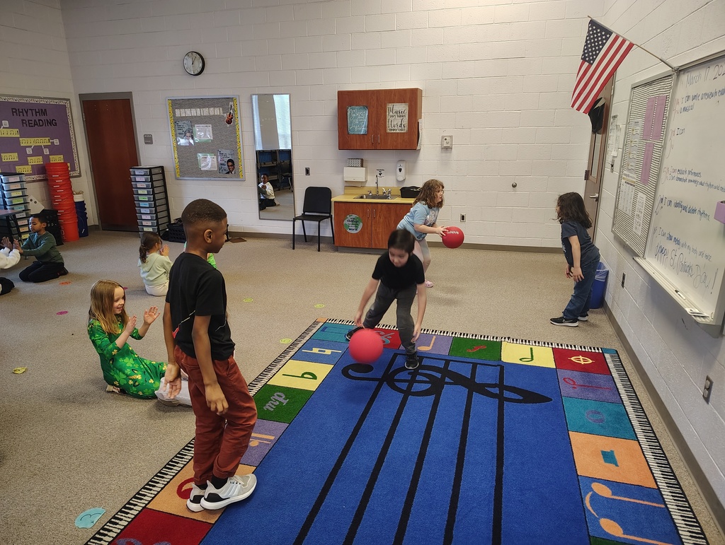 students in a music room using a red kick ball