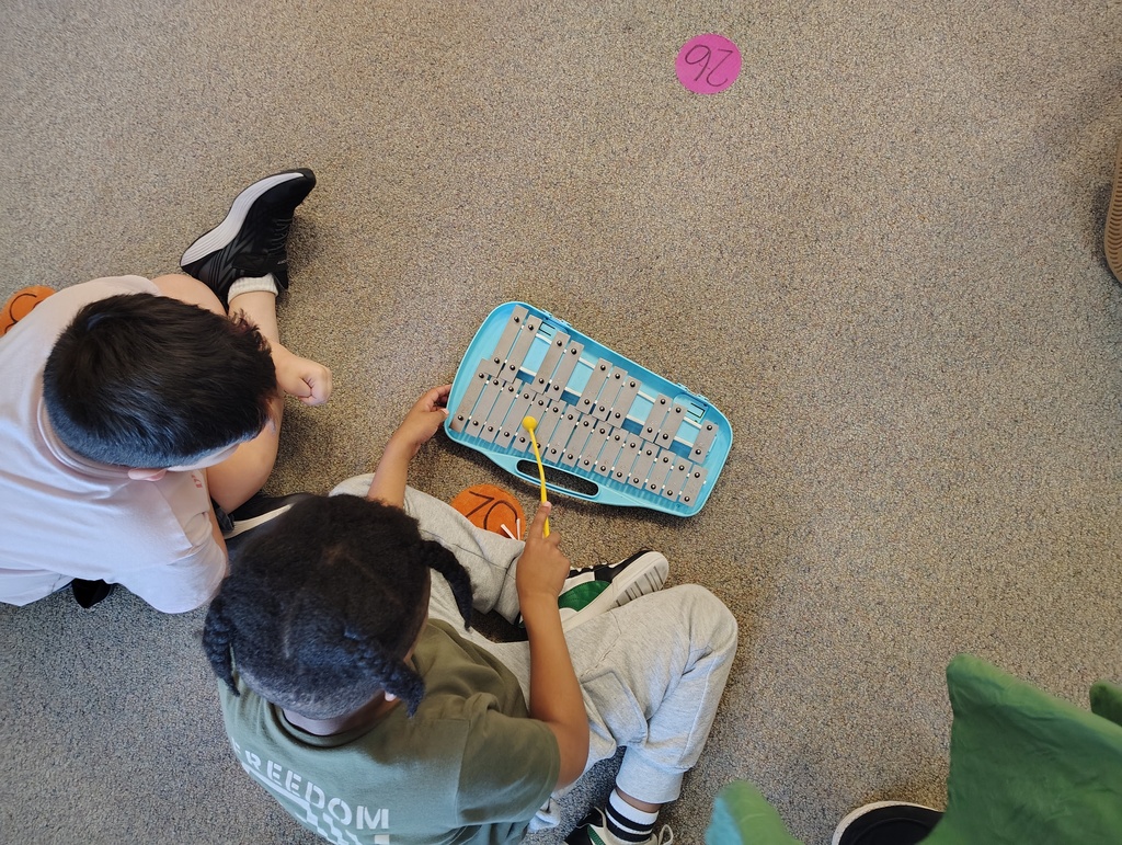 Students sitting and playing a silver and blue glockenspiel