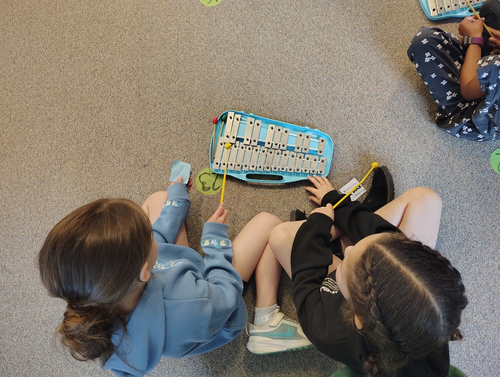 Students sitting and playing a silver and blue glockenspiel