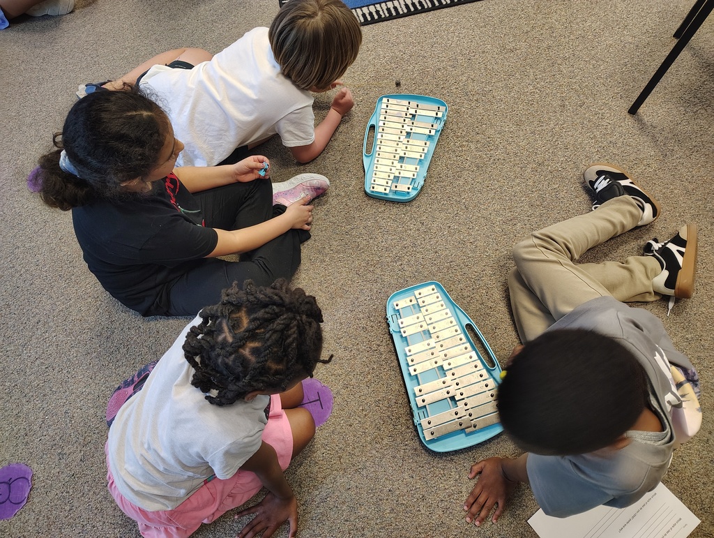 Students sitting and playing a silver and blue glockenspiel