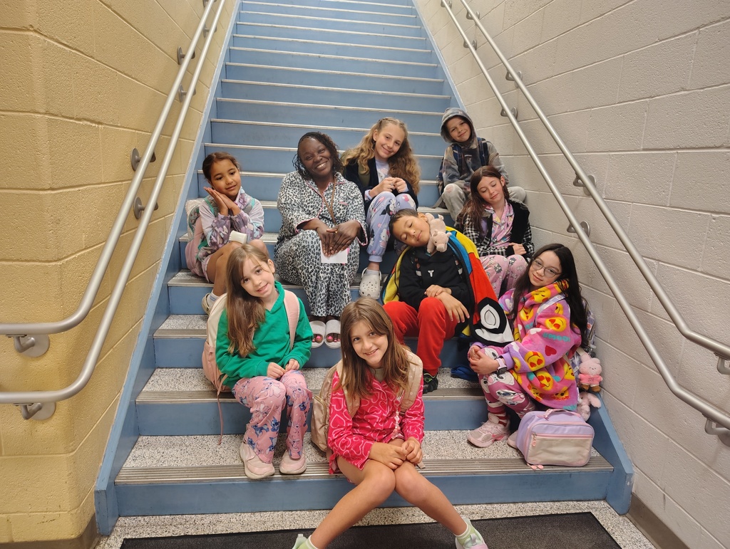 students and principal in fun pajamas, posing on the stairs