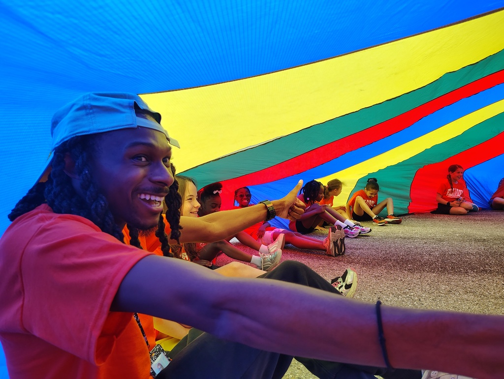 a teacher and students sitting under a parachute