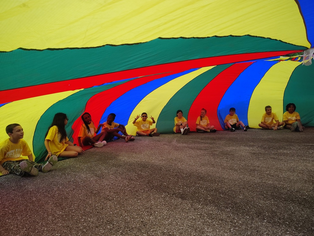 students sitting on the ground under a parachute