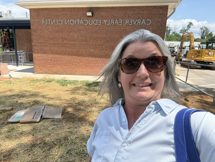 Principal Hamlin taking a selfie outside of the building in front of the new sign for Carver