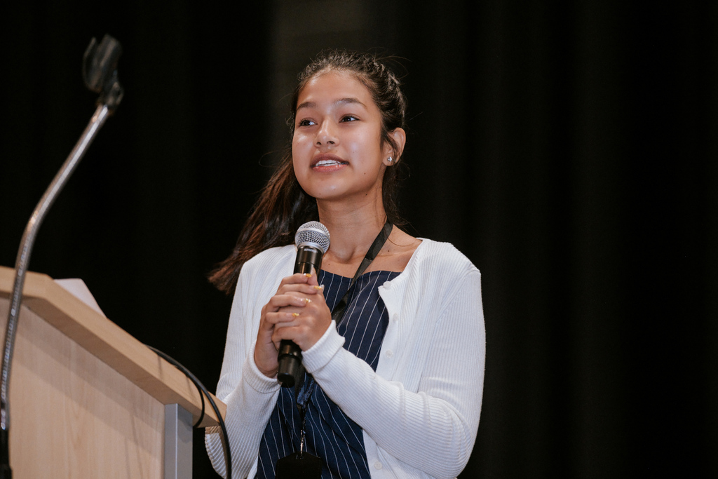 AACPS Mentoring Conference 2026: Student Sham Bohara stands at a podium, holding a microphone, and speaks.