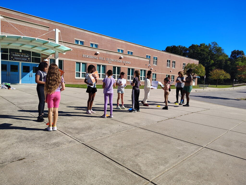 Students standing in two lines facing each other in front of school building