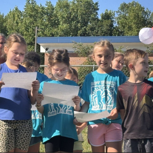A group of students standing outside singing a song