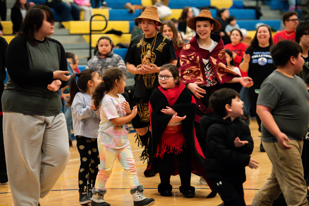 students in regalia dancing in gym