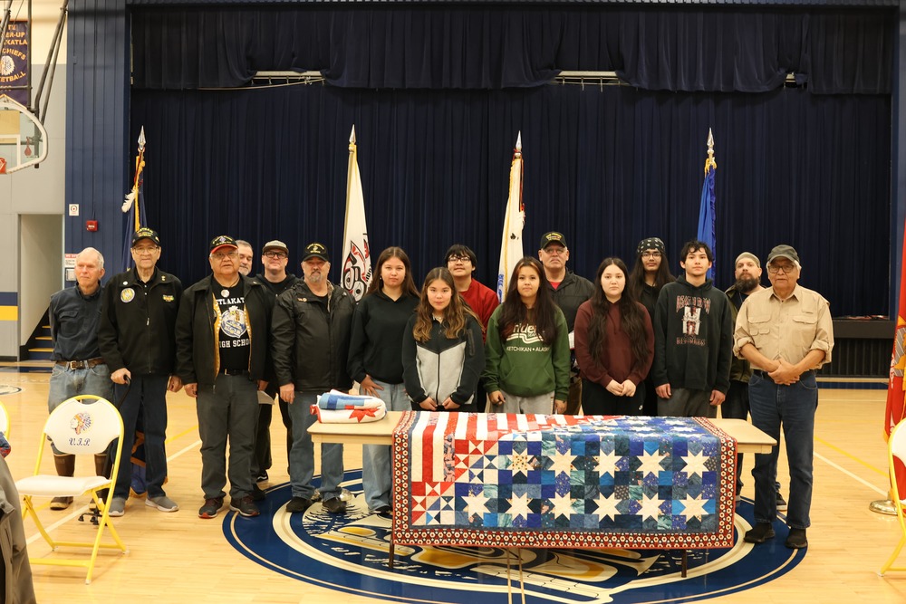 veterans with students and quilt in front of table