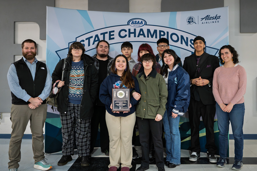students holding a plaque in front of banner