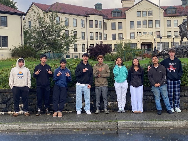 students in front of a hotel smiling at camera