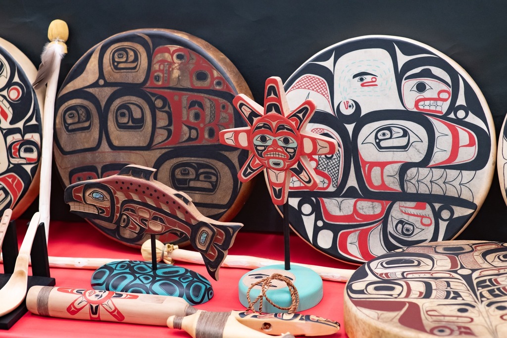 handmade formline artwork including drums, carved fish, a sun, an dmore