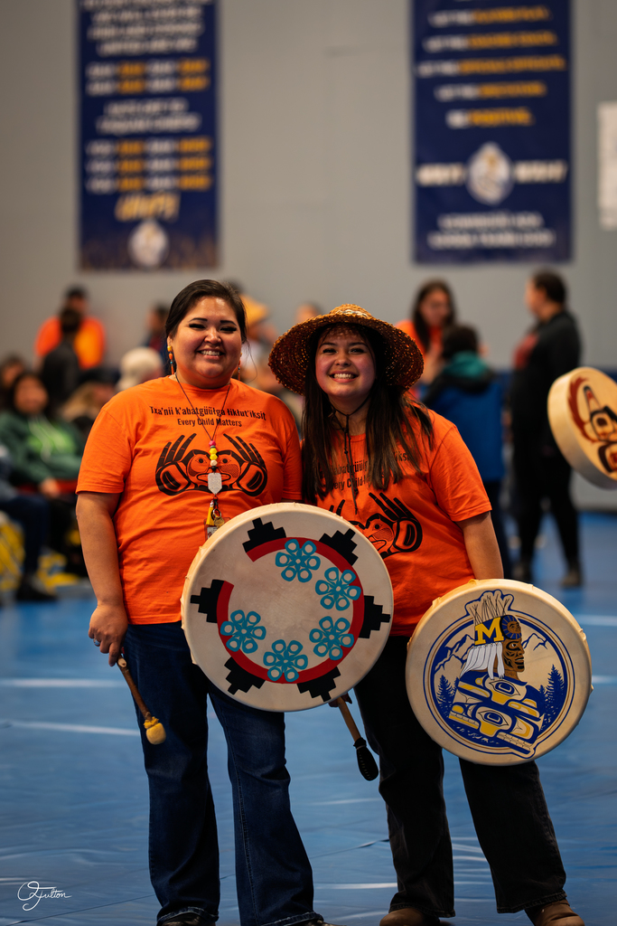 student and adult holding drums wearing orange