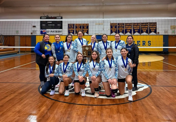 smiling volleyball players in gym with trophy 