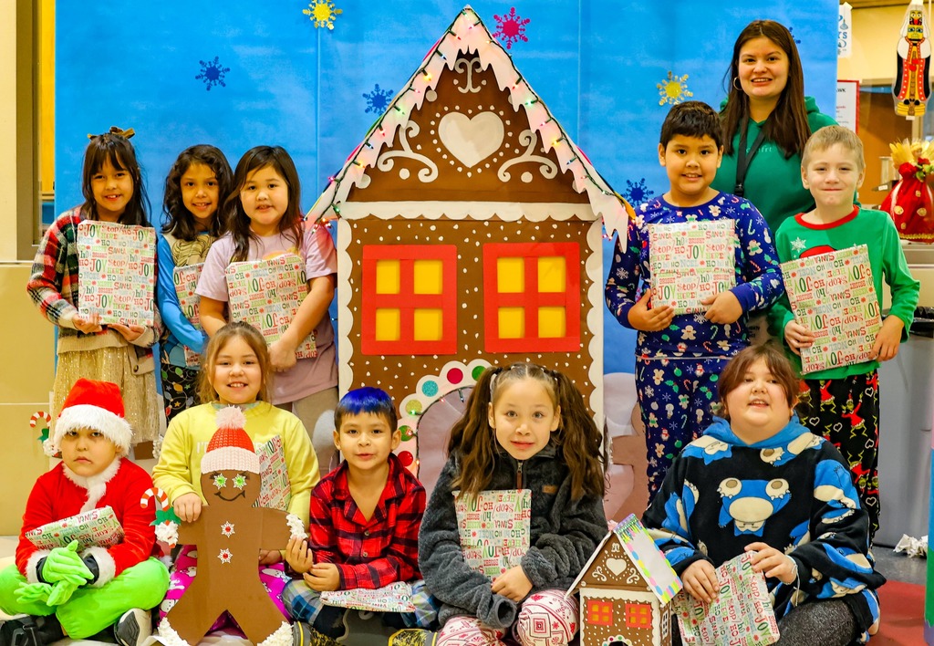 students in front of gingerbread house
