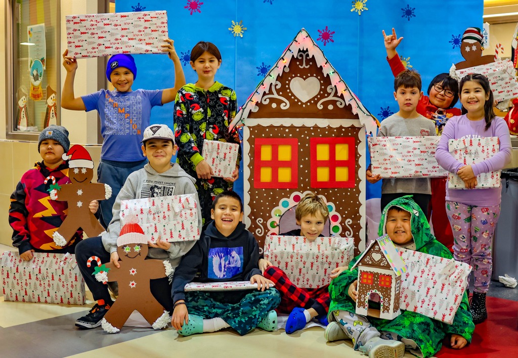 students in front of gingerbread house