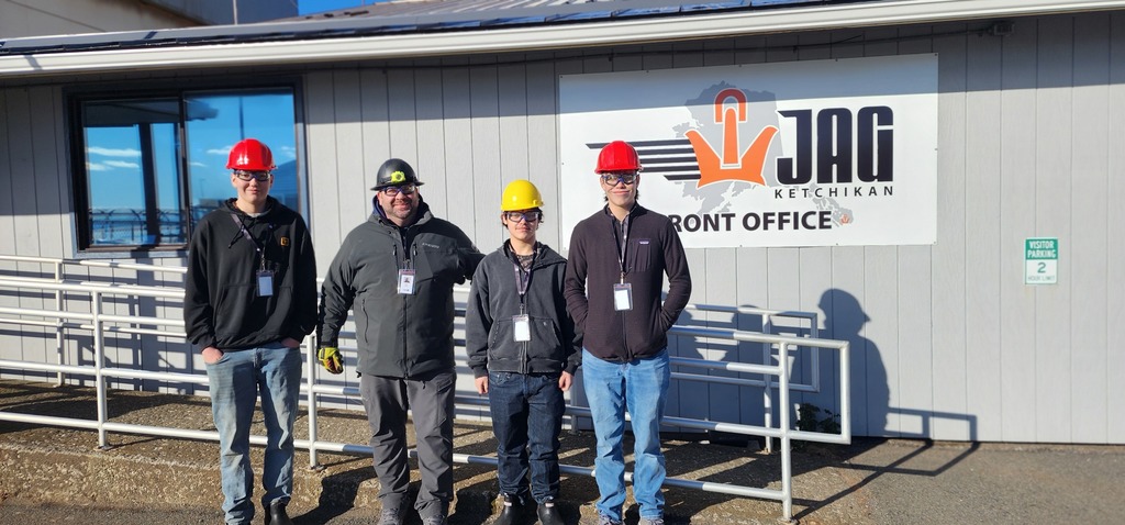 students in front of building with hard hats