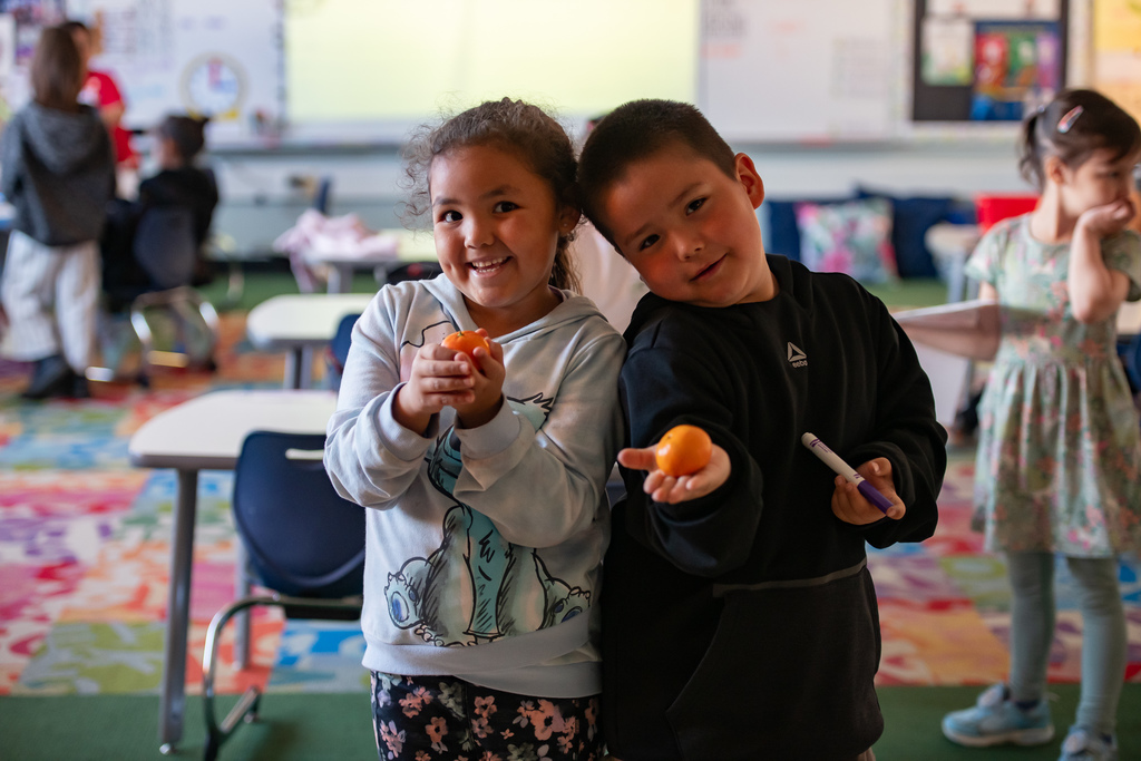 students holding a tangerine in a classroom