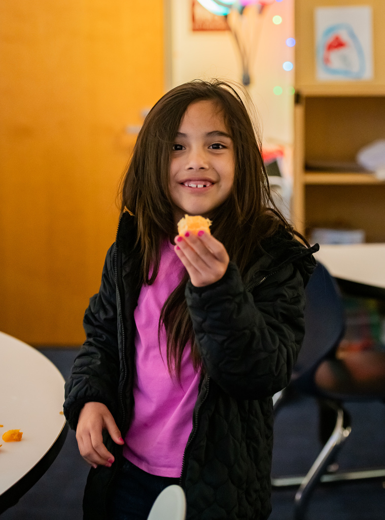 student eating a tangerine in a classroom