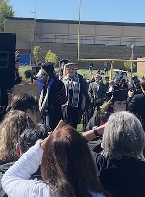 students walking across graduation stage outside.