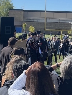students walking across graduation stage outside.