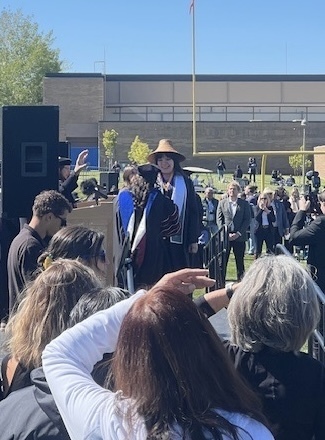 students walking across graduation stage outside.