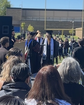 students walking across graduation stage outside.