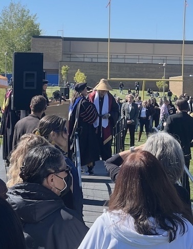 students walking across graduation stage outside.