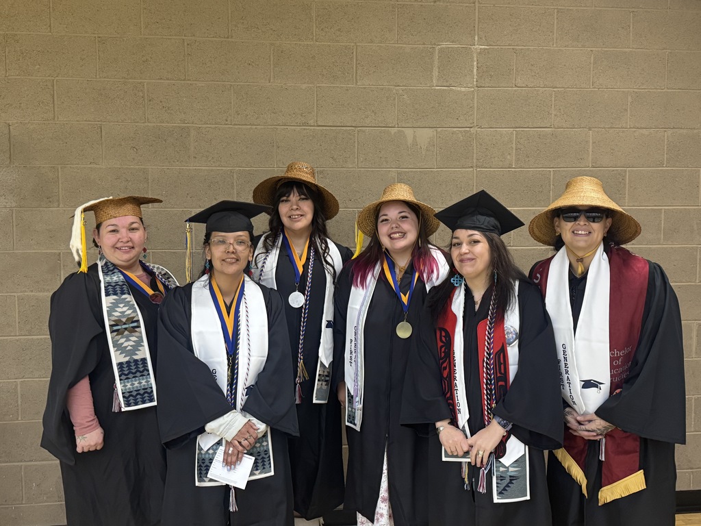 women in graduation caps and gowns, some wearing cedar hats, at a graduation ceremony.