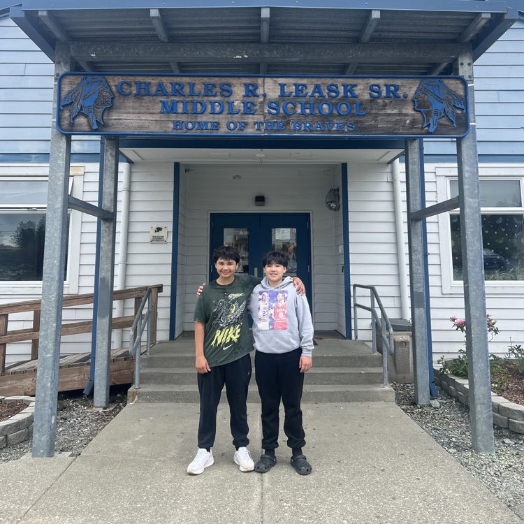 two boys standing in front of a school