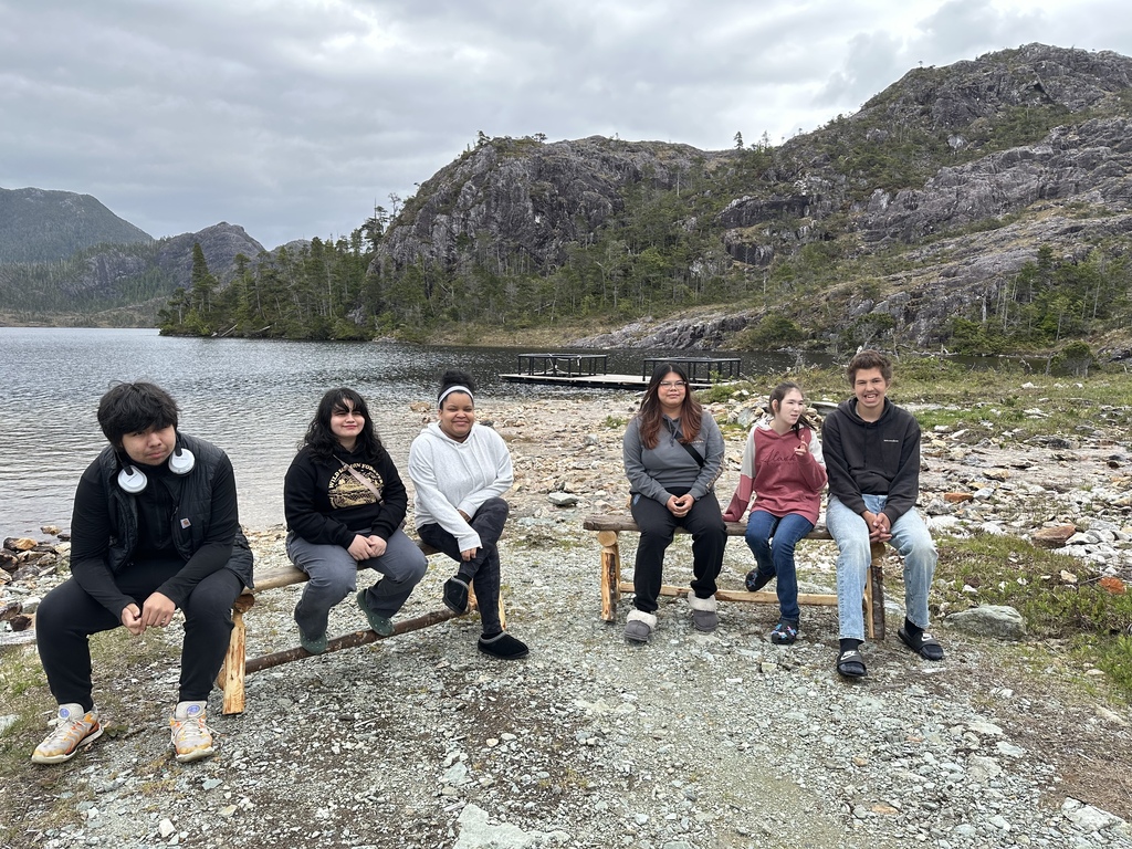 students sitting on bench in front of a lake
