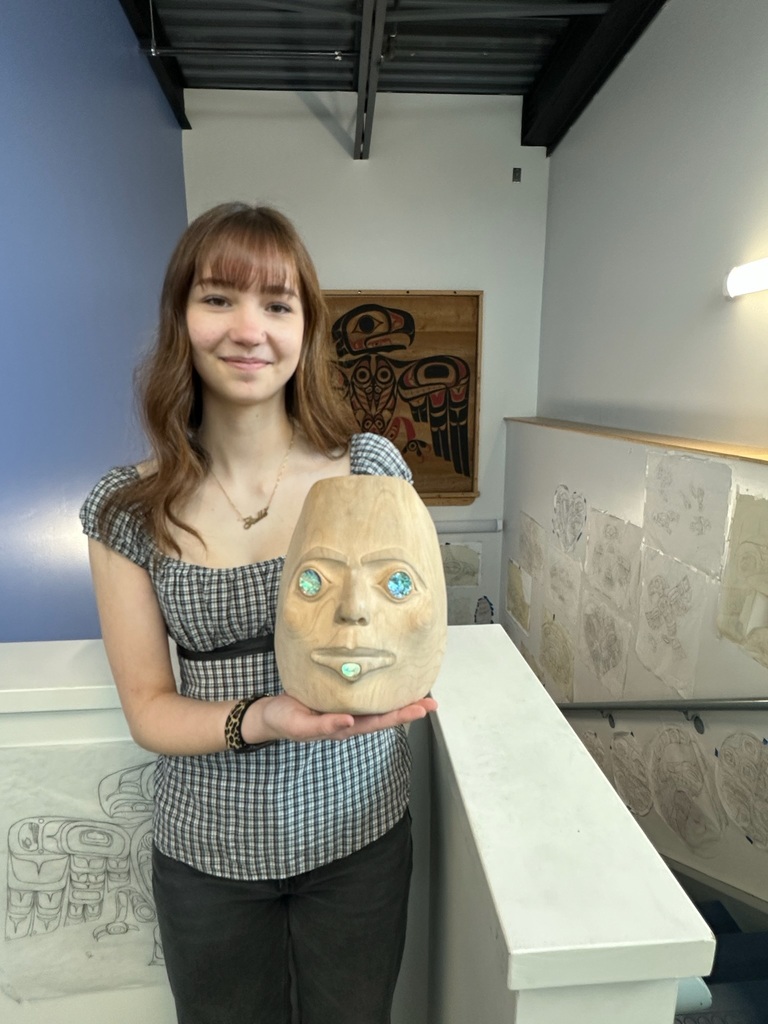 student holding up carved mask