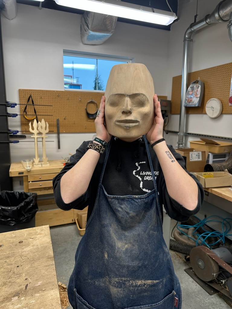 student holding up carved mask in a shop