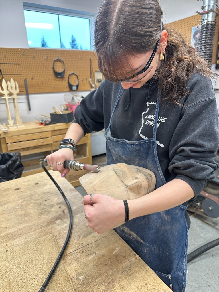 student carving a mask with a sander