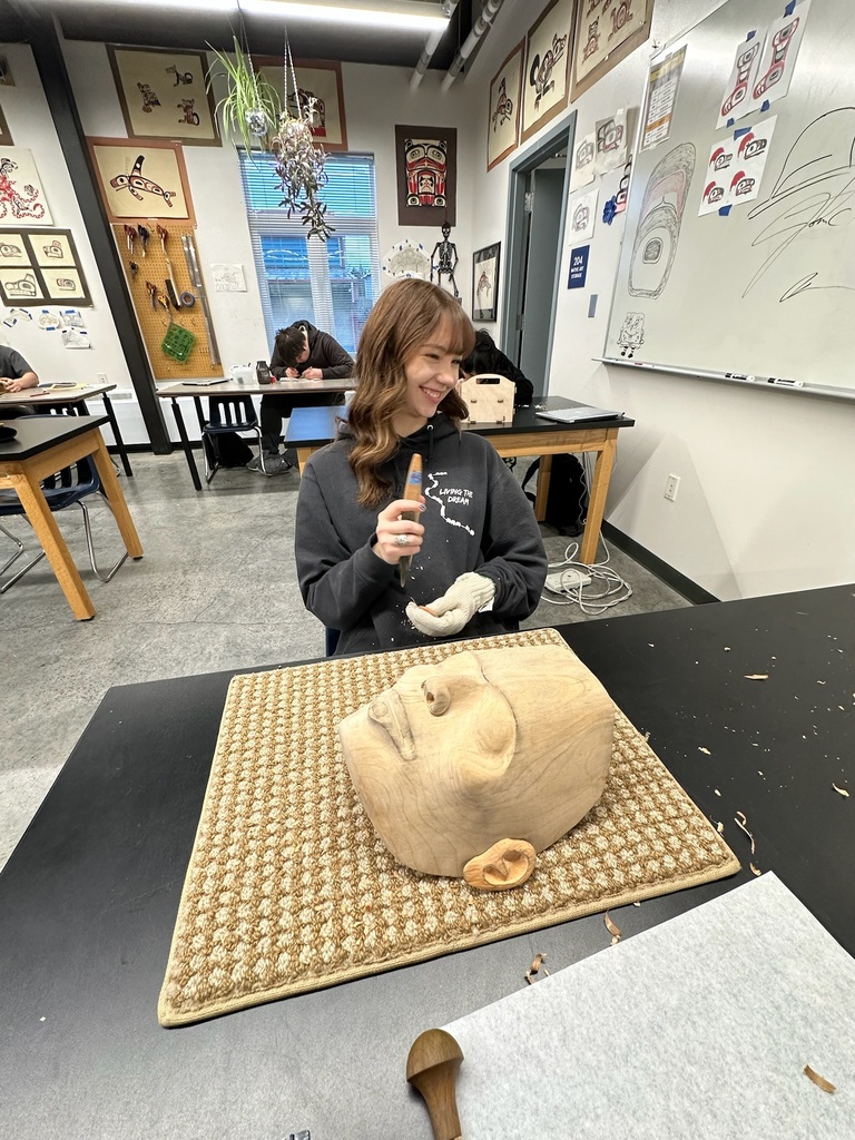 student smiling while carving a mask