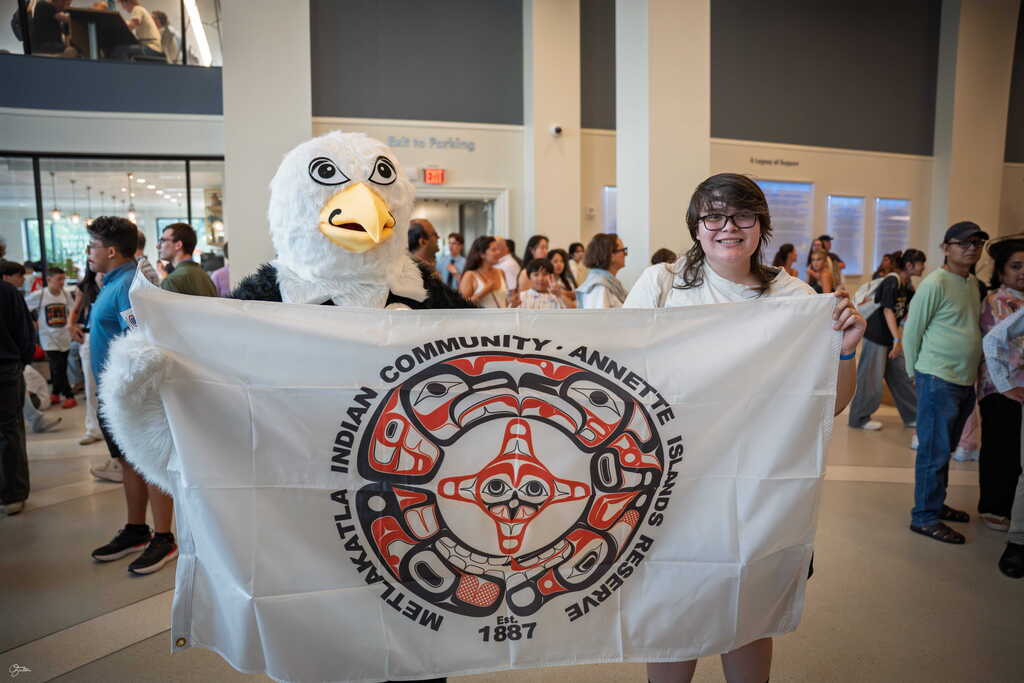 student holding up flag with person in eagle costume