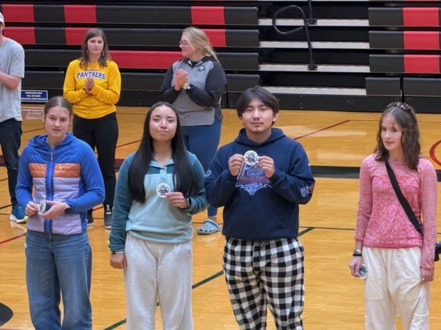 students holding up stickers in a gym
