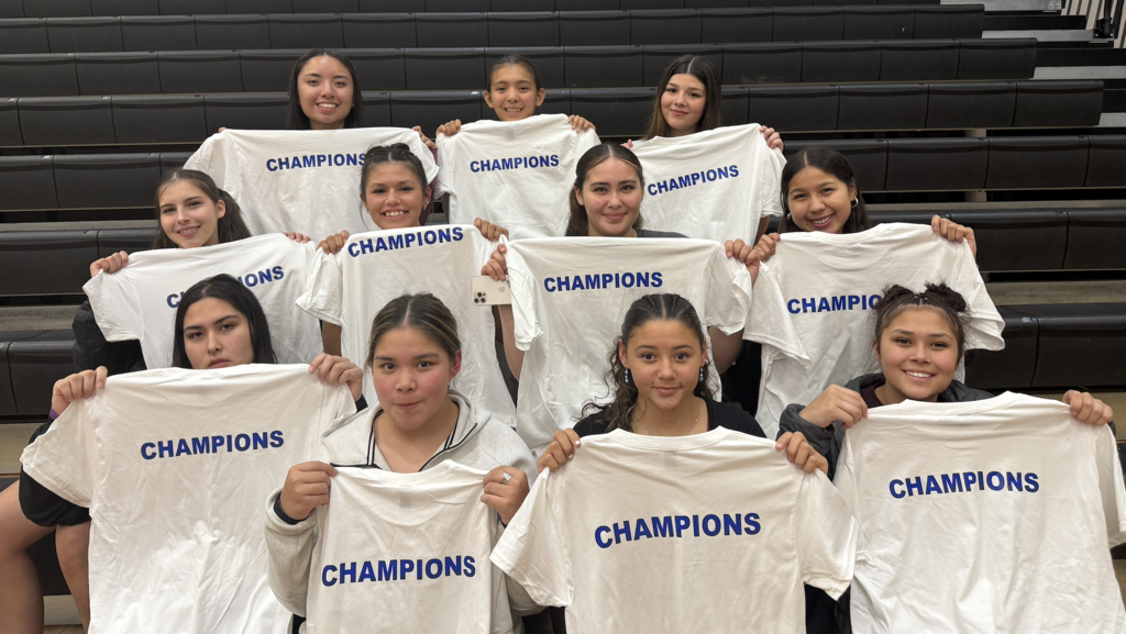 girls holding up champions shirts