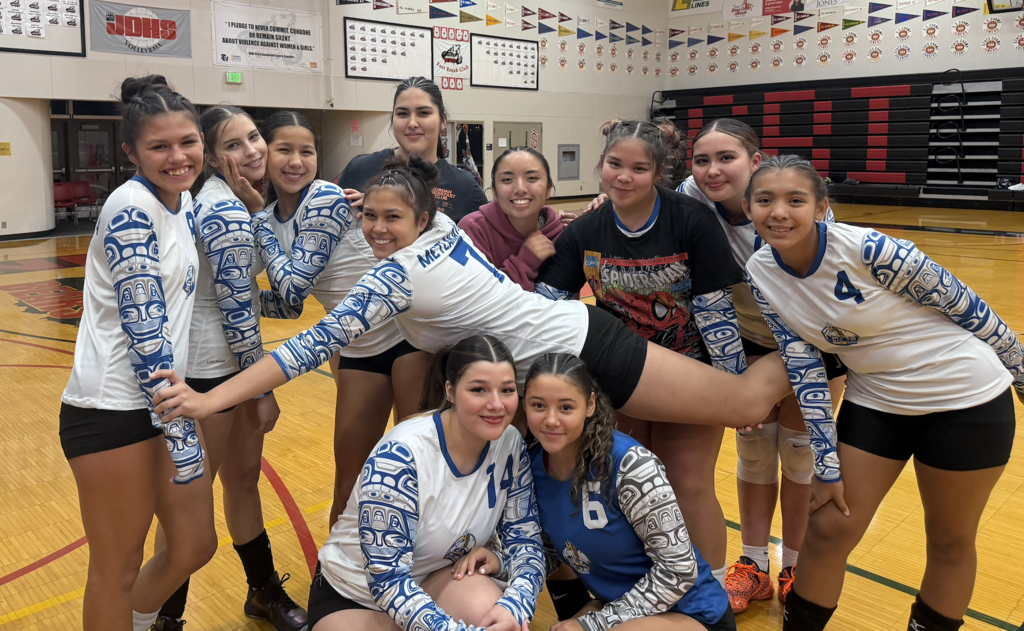 girls in volleyball uniforms posing and smiling