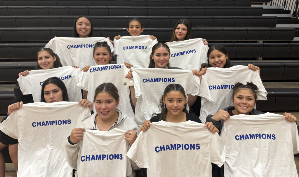 girls holding up champions shirts