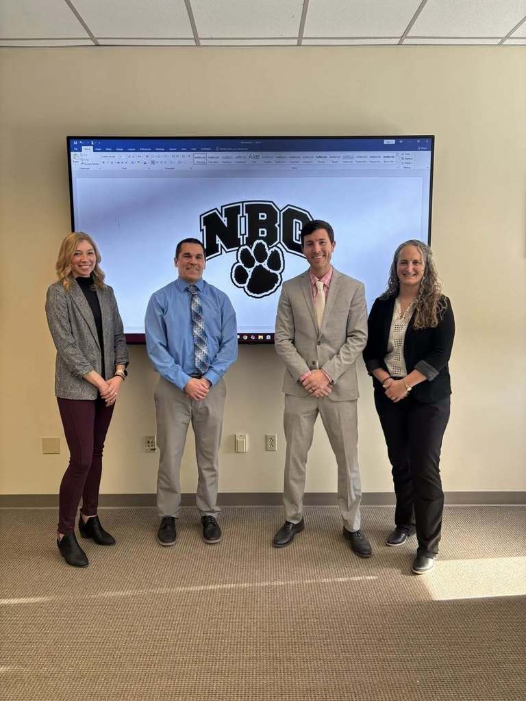 Four people standing in front of a presentation screen