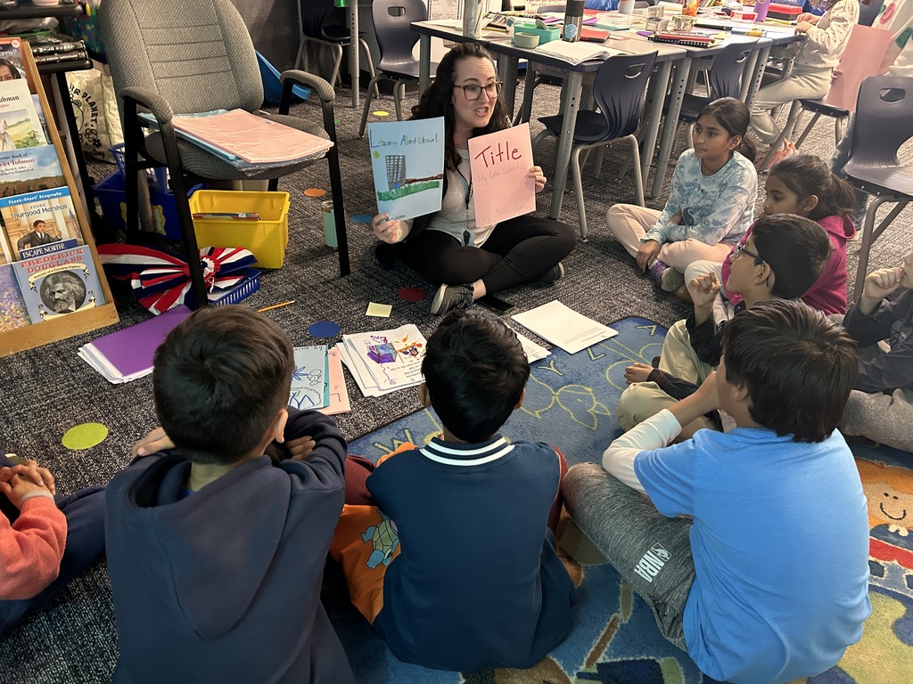 Mrs. Coon meeting with students on the rug giving instruction.