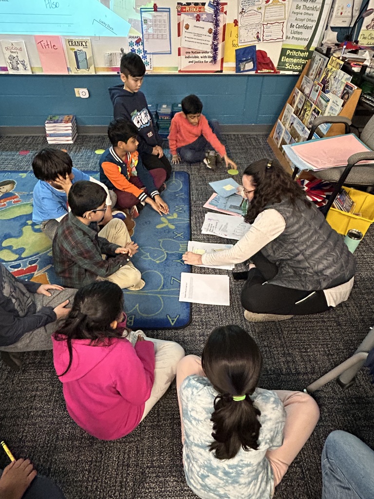 Mrs. Coon meeting with small groups on the rug.