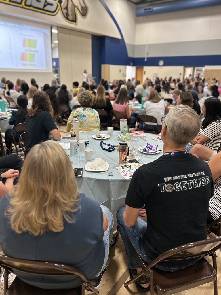 Staff listening and sitting at tables.