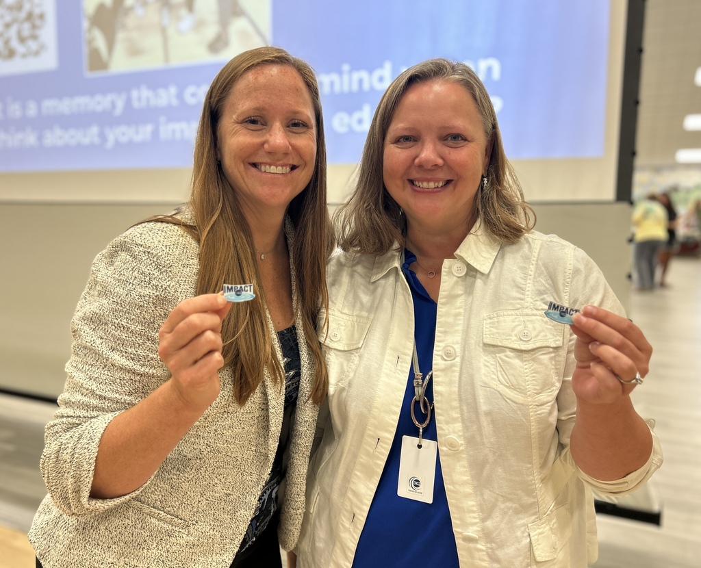 Two women holding a pin.