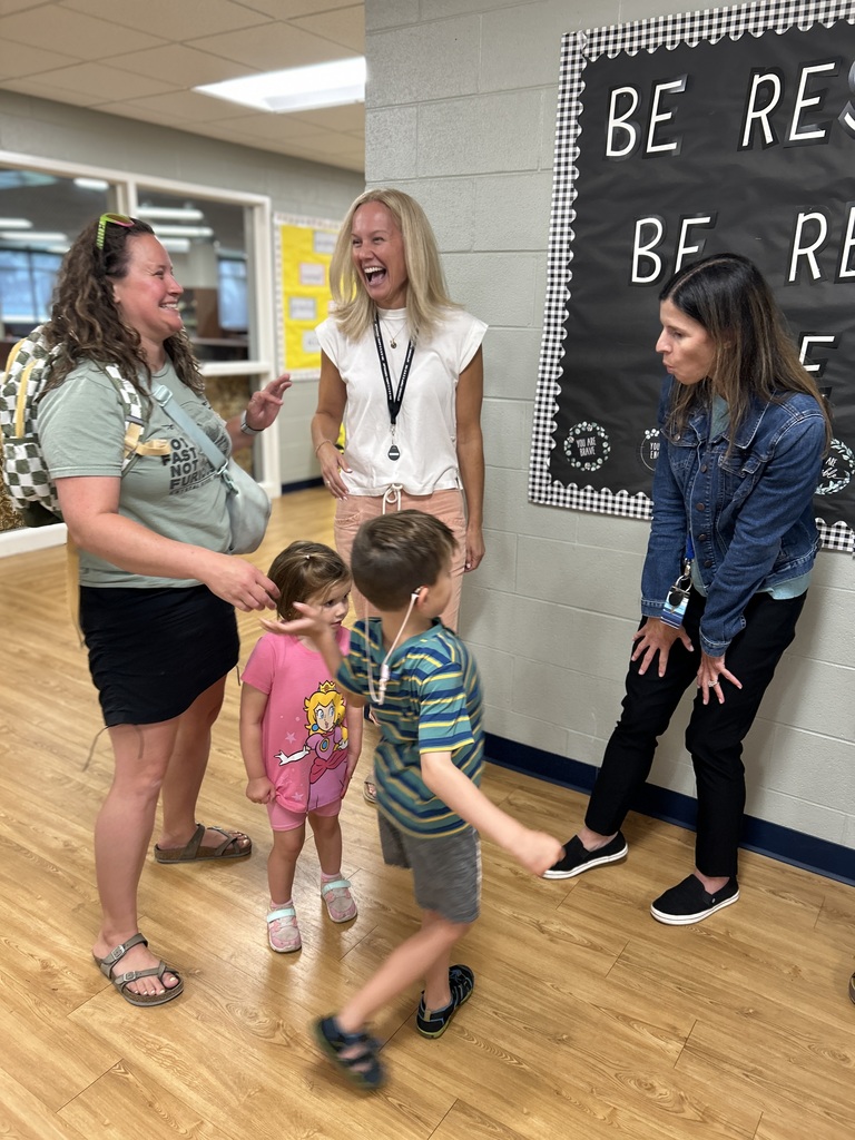 Family laughing together in a hallway with teachers.
