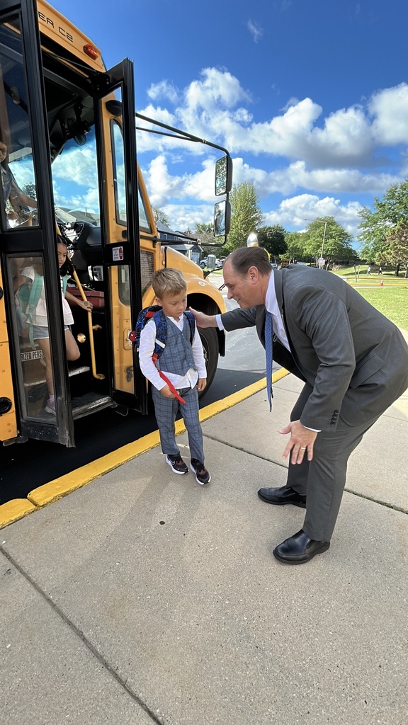 Principal greeting a kid off the bus.