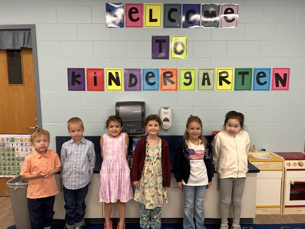 Students standing in front of a kindergarten sign.