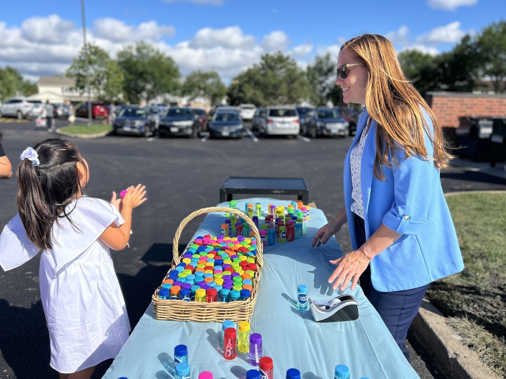 Dr. McIntyre greets a student at a table with bubbles.