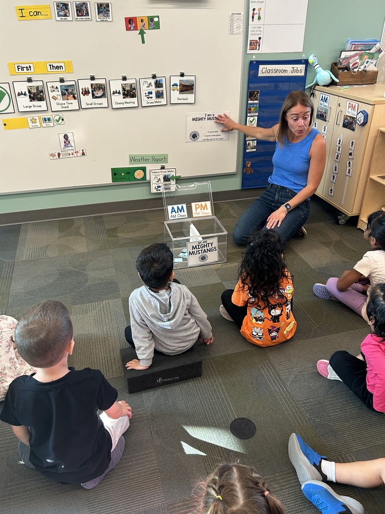 Teacher sitting on the rug with her students.